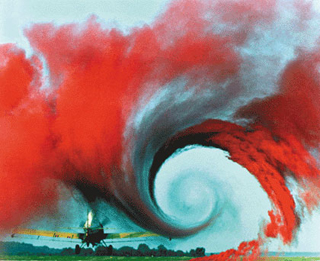 A small aircraft with a bright red vortex of dust behind it. A small aircraft with a bright red vortex of dust behind it.