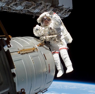 Photograph of astronaut outside space station. Photograph of astronaut outside space station.