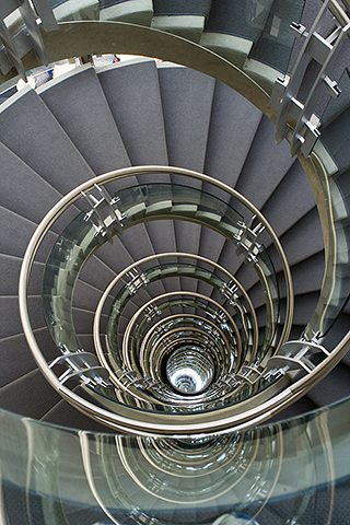 View from the top and down the center of a spiral staircase, made of concrete and glass. View from the top and down the center of a spiral staircase, made of concrete and glass.