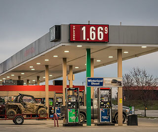 A photo of a gas station with the price of gas displayed. A pickup truck hauling an ATV is in the background. A photo of a gas station with the price of gas displayed. A pickup truck hauling an ATV is in the background.