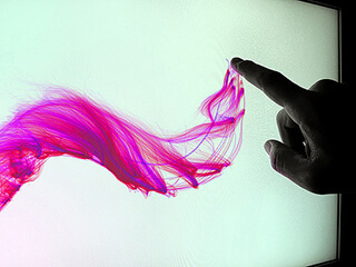 A person's finger creates a pink wave-like image on a touchscreen. A person's finger creates a pink wave-like image on a touchscreen.
