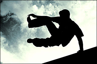 A photograph of the silhouette of a man vaulting over a wall set against a blue sky. A photograph of the silhouette of a man vaulting over a wall set against a blue sky.