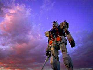 A giant robot standing tall holding a saber in his hand with a purple sunset sky and pink clouds as the background. A giant robot standing tall holding a saber in his hand with a purple sunset sky and pink clouds as the background.