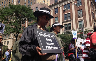 In the midst of other marchers, a black woman holds a sign reading: "March to End Racial Profiling." In the midst of other marchers, a black woman holds a sign reading: "March to End Racial Profiling."