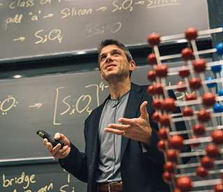 Professor Grossman standing in front of a blackboard with notes written on it at the front of the classroom. Professor Grossman standing in front of a blackboard with notes written on it at the front of the classroom.