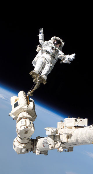 Astronaut Steve Robinson in space, standing on a long robotic arm. Astronaut Steve Robinson in space, standing on a long robotic arm.