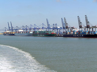 Row of container ships in dock with cranes overhead. Row of container ships in dock with cranes overhead.