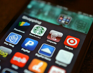 A close-up of the screen of a smartphone that has many colorful shopping apps open. A close-up of the screen of a smartphone that has many colorful shopping apps open.