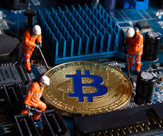 A golden coin sits on a motherboard. Three mini figurines surround the coin with tools. A golden coin sits on a motherboard. Three mini figurines surround the coin with tools.