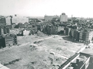 A bird's-eye view of an urban renewal project, with a large barren area abutting a densely-built block of tenements. A bird's-eye view of an urban renewal project, with a large barren area abutting a densely-built block of tenements.