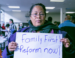 A woman holds up a sign that reads "Family First! Reform now!" A woman holds up a sign that reads "Family First! Reform now!"
