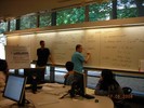 A student writes on the board while the teacher looks on.