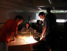 A small beaker sits on a table with a thermometer in it. A bright light shines on the beaker.