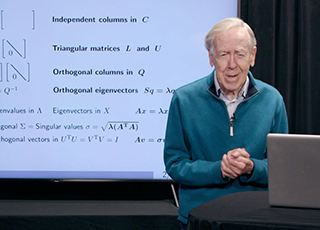 Professor Strang standing behind a podium with a slide screen behind him. Professor Strang standing behind a podium with a slide screen behind him.