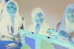 A negative-processed image of three girls sitting at a table.